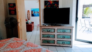 A bedroom with a bed, a TV on a wooden dresser, a fan, and a view of the outside. - Top Floor Large 2 Bedroom  Ocean/Beach Views Vaulted Ceiling Lots of Windows (Cabo San Lucas)