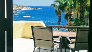 A view from a balcony overlooking a coastal area with palm trees and a clear blue sea. - Top Floor Large 2 Bedroom  Ocean/Beach Views Vaulted Ceiling Lots of Windows (Cabo San Lucas)