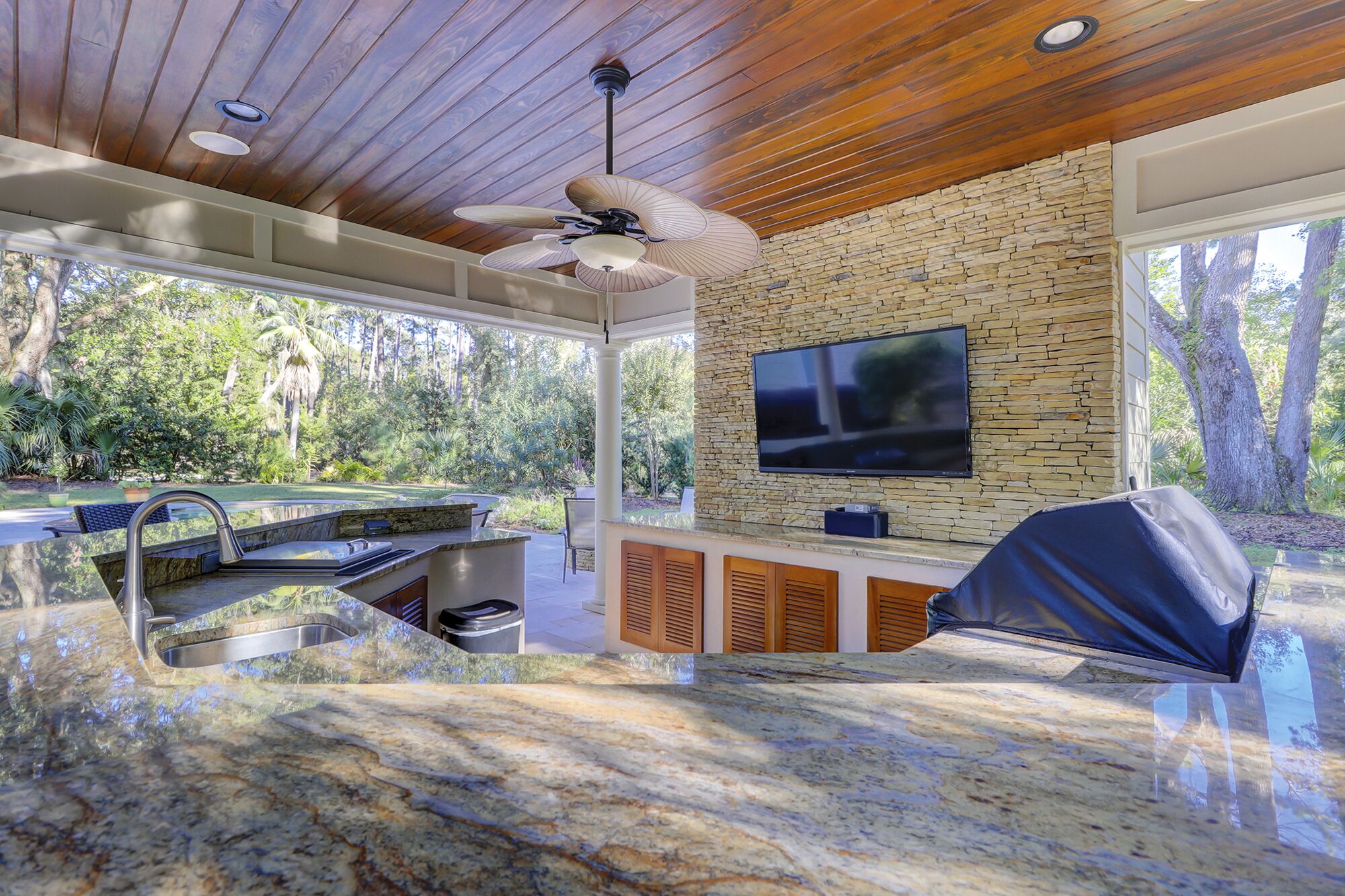 Una cucina moderna con schienale in pietra, TV integrata e ventilatore a soffitto.