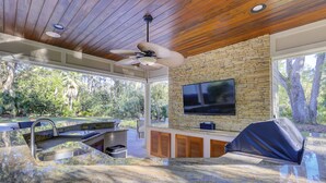 Una cocina moderna con salpicadero de piedra, televisor integrado y ventilador de techo.
