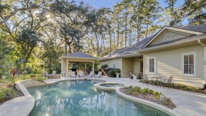 Una casa con piscina, mobiliario exterior y un patio cubierto.