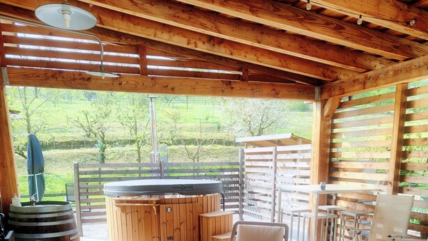 A wooden cabin with a hot tub, outdoor seating, and a view of the surrounding greenery. - A vacation in the midst of nature just a stone's throw from Alba? (Alba)