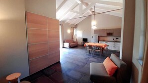 A spacious living area with a sofa, a dining table, and a kitchen in the background. - A vacation in the midst of nature just a stone's throw from Alba? (Alba)