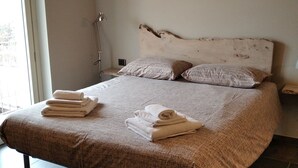 A bedroom with a bed, pillows, and folded towels. - A vacation in the midst of nature just a stone's throw from Alba? (Alba)