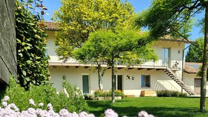 A two-story building with a balcony, a staircase, and a well-maintained garden with purple flowers. - A vacation in the midst of nature just a stone's throw from Alba? (Alba)