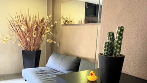 A modern living room with a grey sofa, a black coffee table, a potted plant, and a small rubber duck. - S01 KING SUITE PREMIUM! IN FRONT OF THE TÉC DE MONTERREY CAMPUS EDO MEX (Ciudad López Mateos)