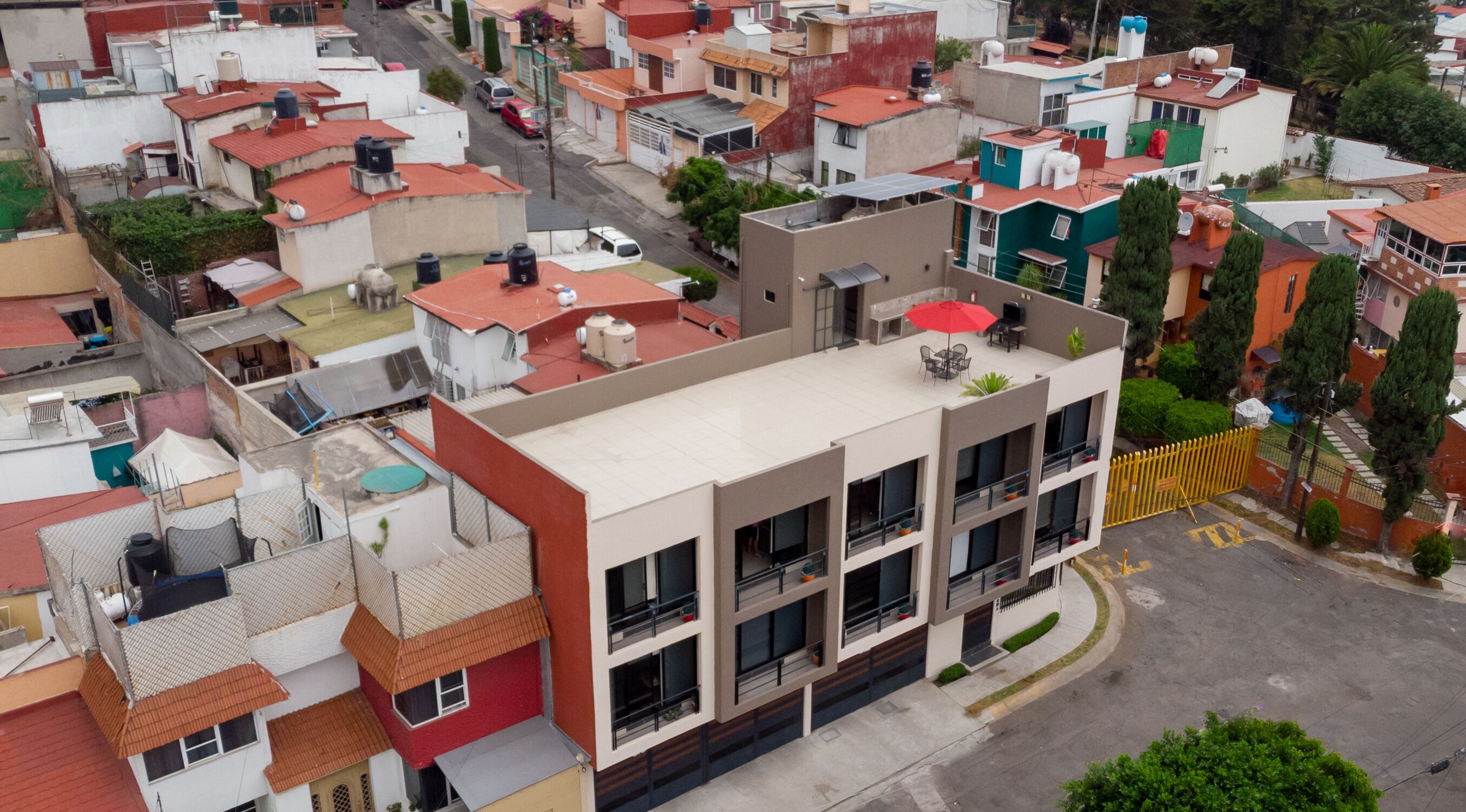 A multi-story residential building with balconies, a gated entrance, and a street view.