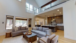 A spacious living area with a high ceiling, large windows, and a view of the outdoors. - Caldera Getaway with Access to Forest House (Sunriver)