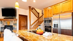 A kitchen with granite countertops, a stainless steel refrigerator, a microwave, and a stove.