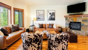 A cozy living room with a fireplace, leather sofa, and cowhide chairs.