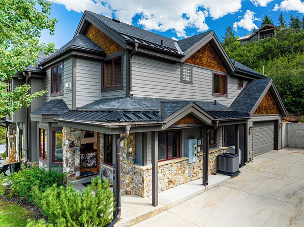 Une maison à deux étages, avec des fondations en pierre, un garage et une véranda.