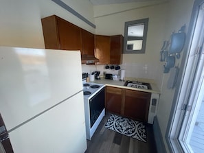 Una cocina compacta con armarios de madera, un refrigerador blanco, una estufa y un lavamanos.