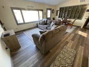 A living room with a sofa, a coffee table, and a dining area with chairs and a table.