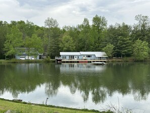A lakeside cabin with a dock, surrounded by dense forest.