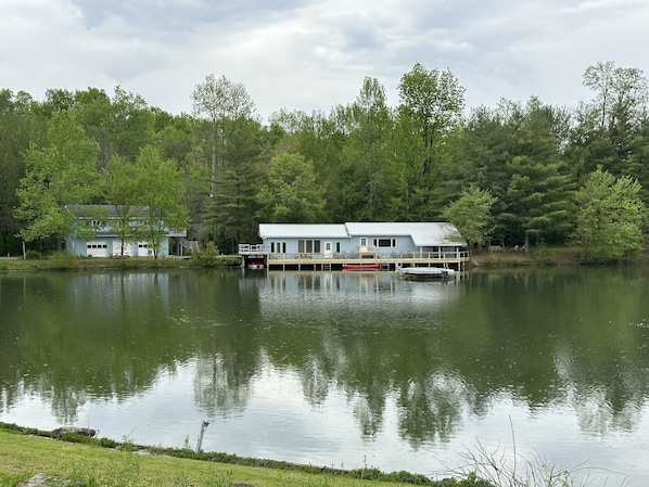 Un chalet au bord du lac, doté d’un quai, et entouré d’une forêt dense.