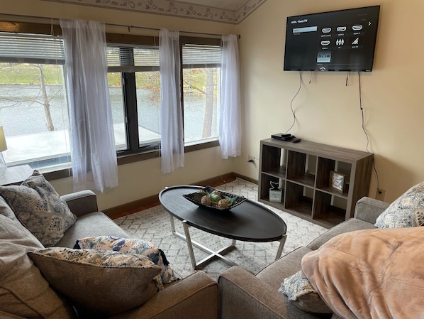 Una sala de estar con una televisión de pantalla plana montada en la pared, una mesa de centro y dos sofás.