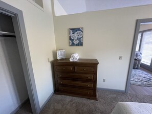A bedroom with a wooden dresser, a wall clock, and a painting.