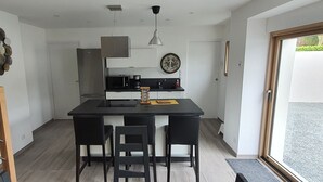 Una cocina moderna con una isla central, sillas negras y una escalera de madera.