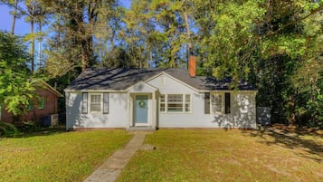 A single-story house with a front porch, a chimney, and a small attached garage.