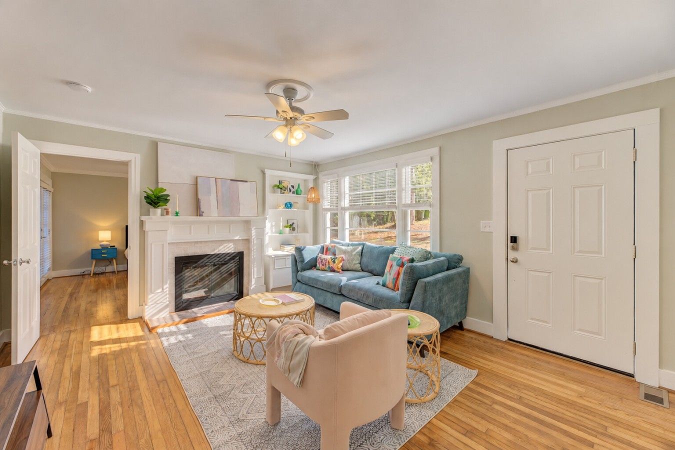 A living room with a fireplace, a blue sofa, a round coffee table, and a ceiling fan.