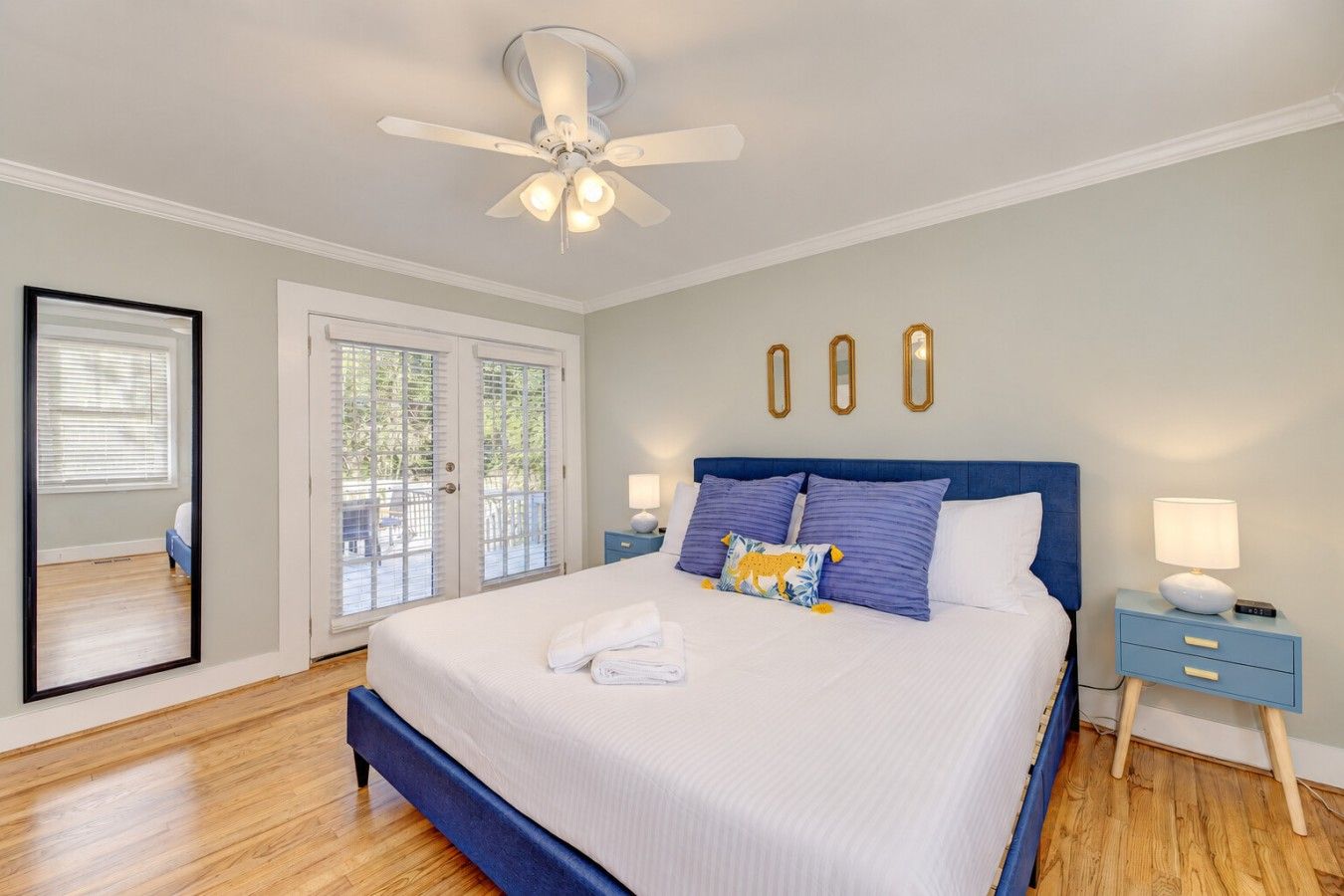 A bedroom with a bed, a ceiling fan, a nightstand, and a door leading to an outdoor area.