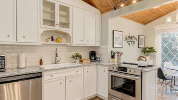 A modern kitchen with white cabinetry, a built-in oven, and a skylight.