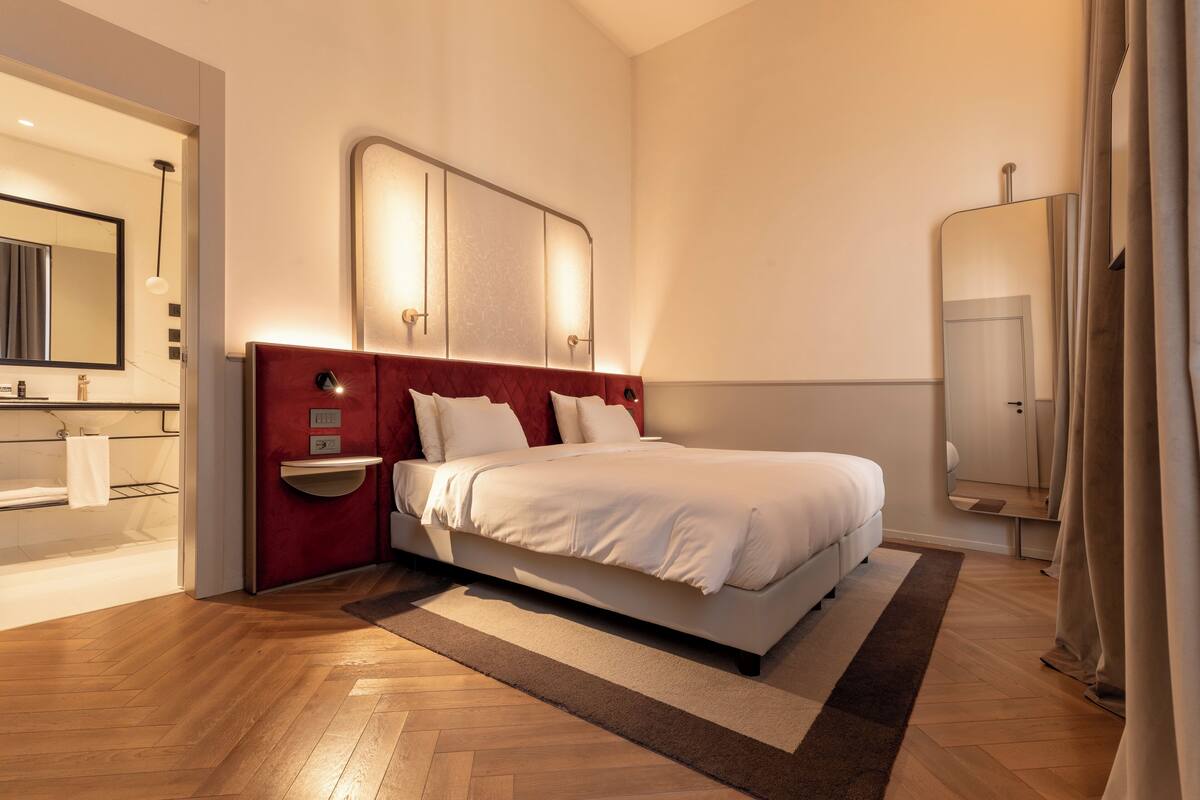 Een moderne hotelkamer met een groot bed, een inbouwkamer en een grote spiegel.