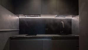 A modern kitchen with dark cabinetry, a stainless steel countertop, and a built-in range hood.
