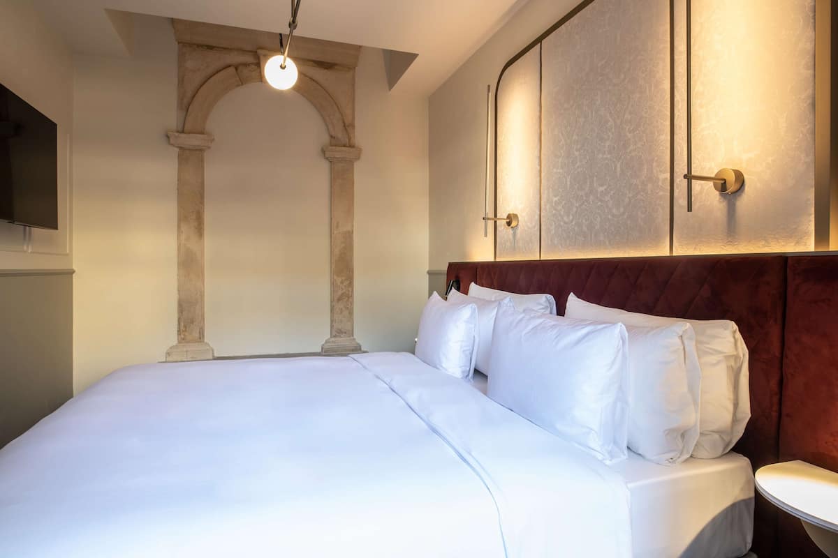 Een hotelkamer met een groot bed, een televisie en een decoratieve boog.