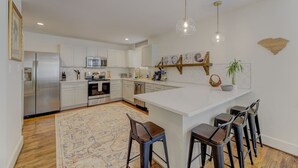 A modern kitchen with white cabinetry, a central island with bar stools, and pendant lighting.