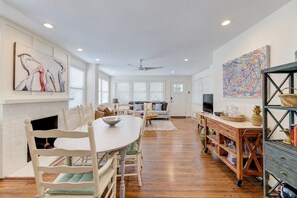 Amplia sala de estar con mesa de comedor, sillas, chimenea, televisor y obras de arte en las paredes.