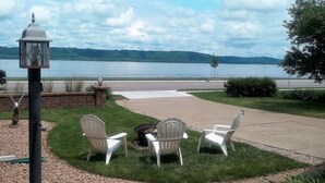 Un patio con mobiliario exterior, un hogar para fogata y vistas a un lago.