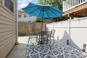 Relax in a serene patio setting with a comfortable table and chairs, shaded by a stylish umbrella.