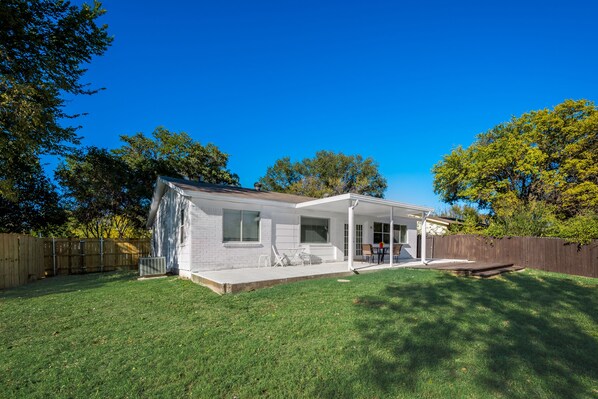 A single-story house with a covered patio, a fenced backyard, and a wooden deck.