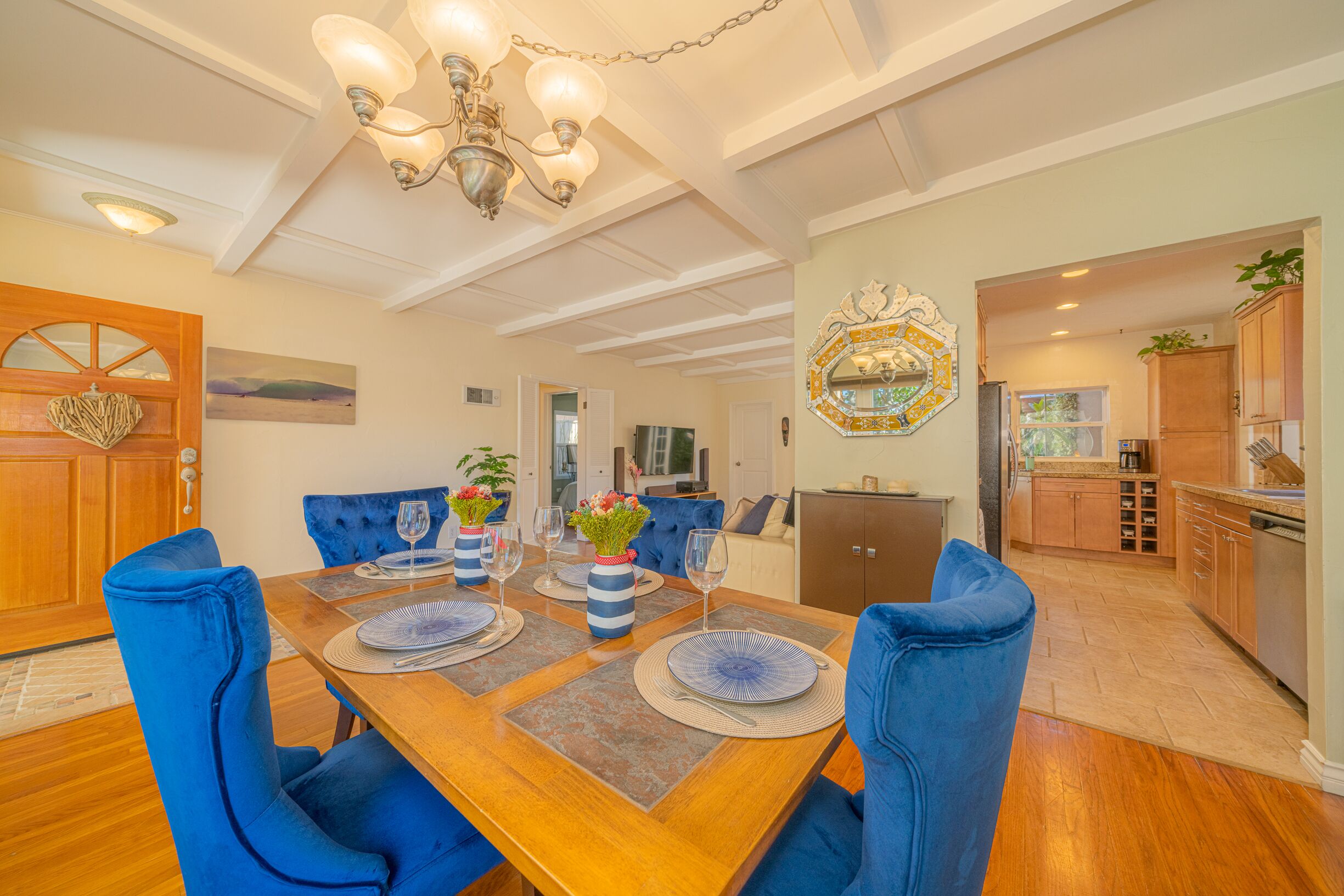 A dining area with a wooden table set for four, blue upholstered chairs, and a chandelier.
