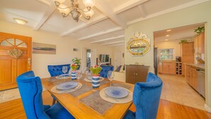 A dining area with a wooden table set for four, blue upholstered chairs, and a chandelier.