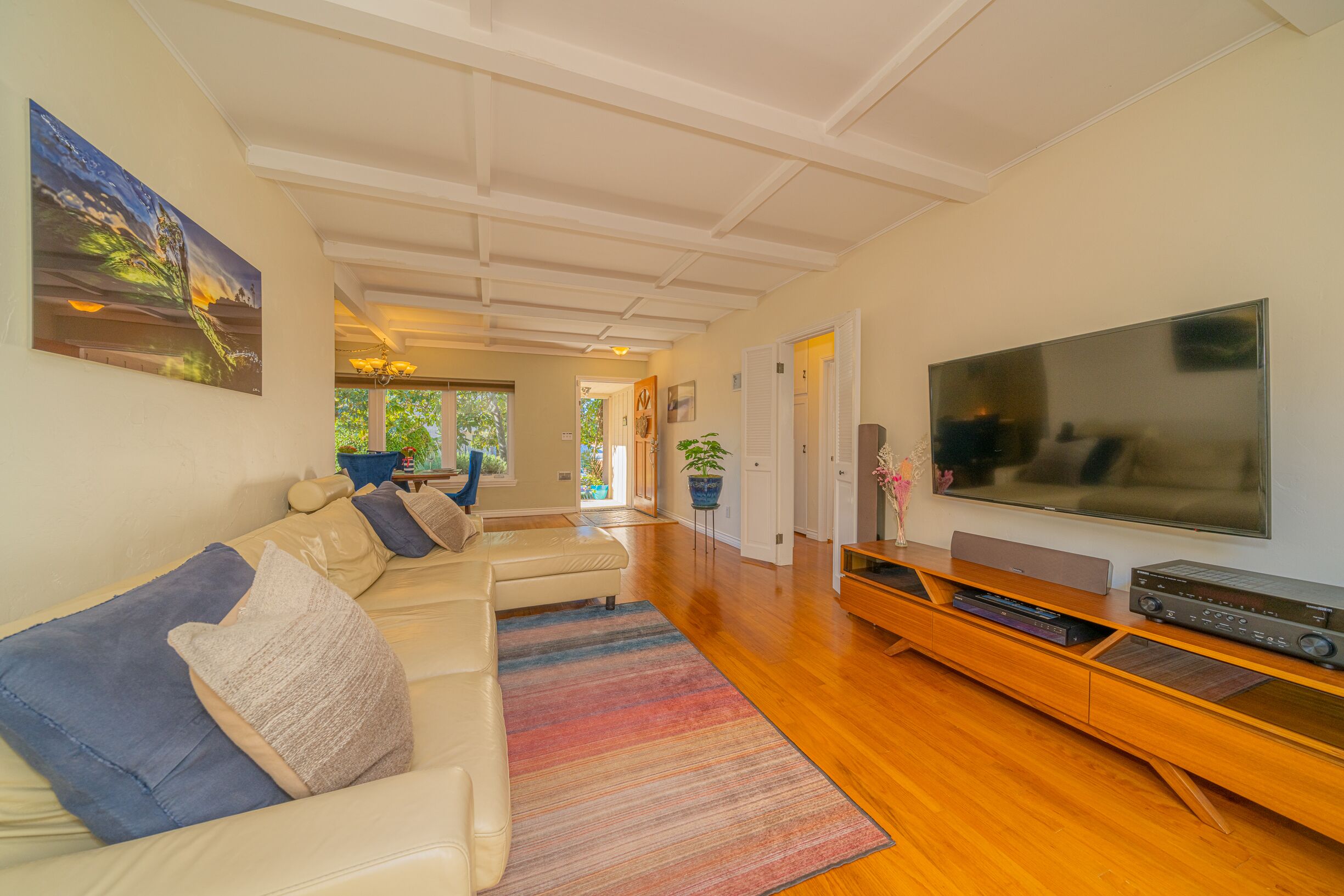 Una sala de estar moderna con un televisor de pantalla plana grande, un sofá color beige y un mueble de entretenimiento de madera.