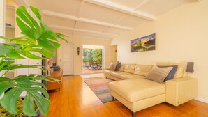 A living room with a beige sofa, a potted plant, and a wooden floor.