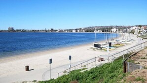 A beach with a clear blue sky, a sandy shore, and a row of sailboats.