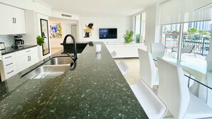 Une cuisine moderne dotée d’un plan de travail en granit noir, de meubles blancs et d’un évier encastré.