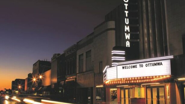 A theater with a marquee reading "Welcome to Ottumwa" and a sign above it that says "Ottumwa."