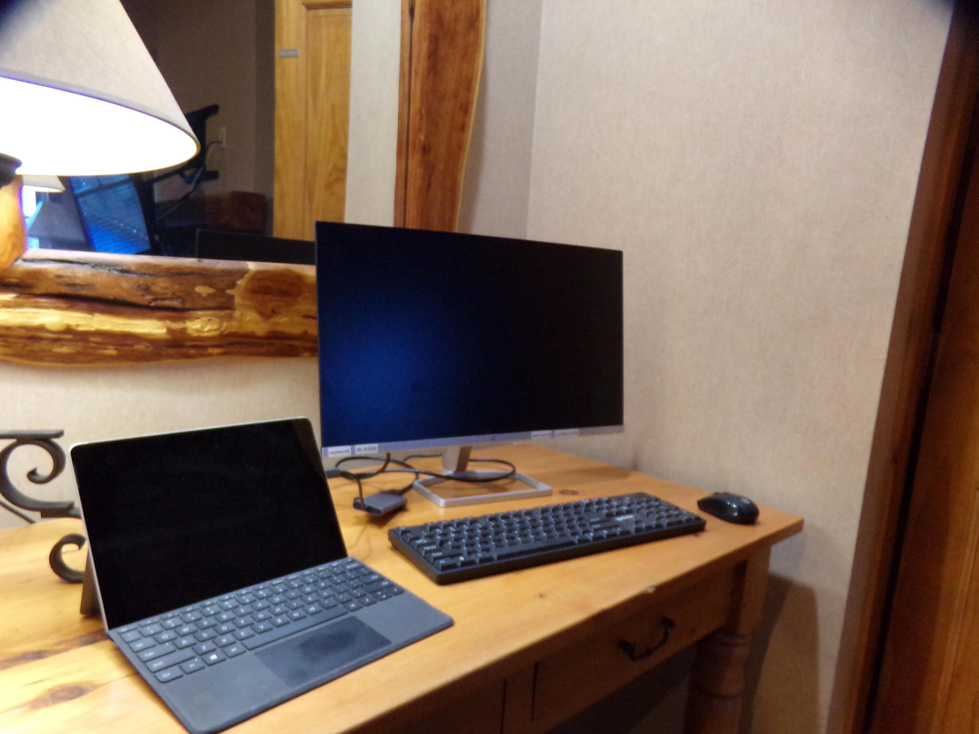 Un escritorio de madera con una computadora portátil, una computadora de escritorio y un teclado.