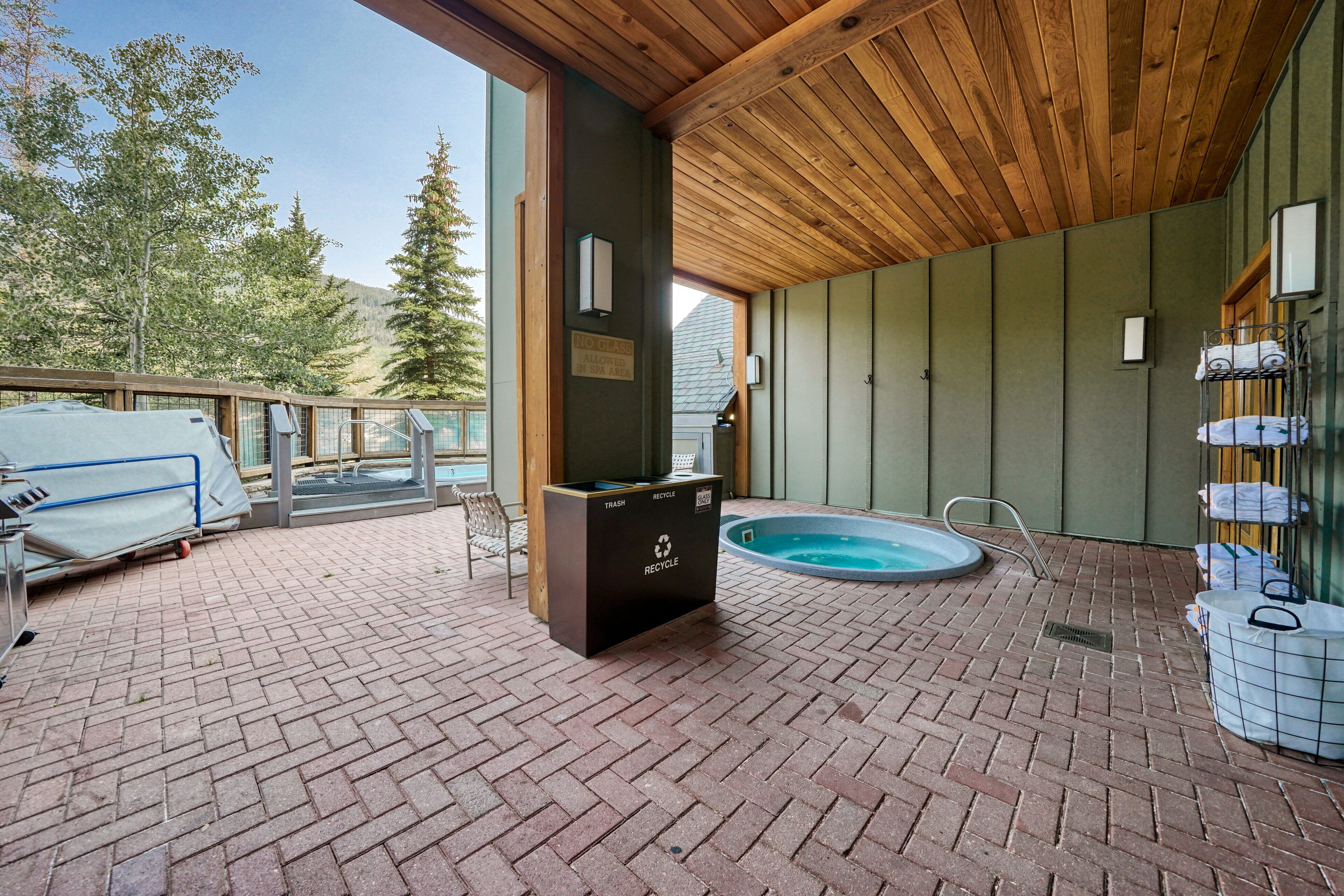 An outdoor patio with a pool, a trash and recycle bin, and a covered seating area.