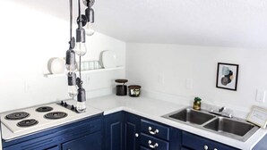 Una cocina con encimeras blancas, armarios azul oscuro, una estufa y dos fregaderos.