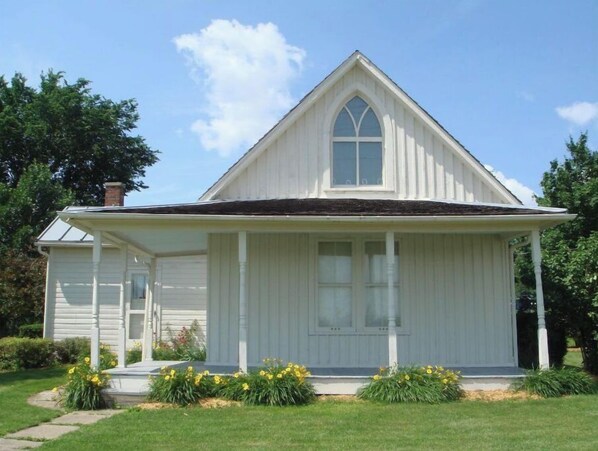 A white two-story house with a gabled roof and a front porch.