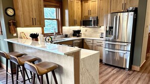 A modern kitchen with wooden cabinets, a stainless steel refrigerator, and a marble countertop. - Private Garage/Walk to the Gondola in 2 Minutes/Pool and Hot Tub/Fitness Room (Keystone)