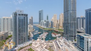 Un immeuble de grande hauteur, avec une marina au premier plan et une vue sur les toits de la ville en arrière-plan.