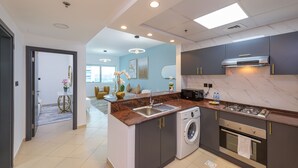 A modern kitchen with a built-in washer and dryer, a stainless steel sink, and a gas stove. - Marco Polo - 1BR with Marina Views, Near Metro & Marina Mall (Dubai)