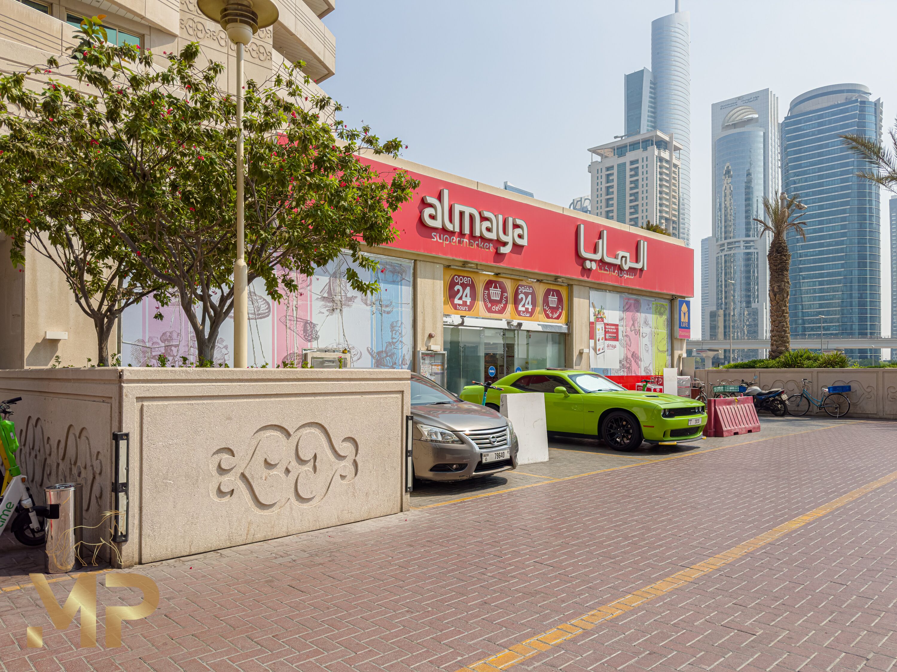 A modern urban street with a prominent 'almay' store, a green sports car, and high-rise buildings in the background.