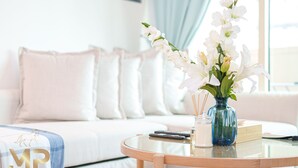 Un soggiorno moderno con un tavolo rotondo in vetro, un divano bianco e un vaso con fiori bianchi.